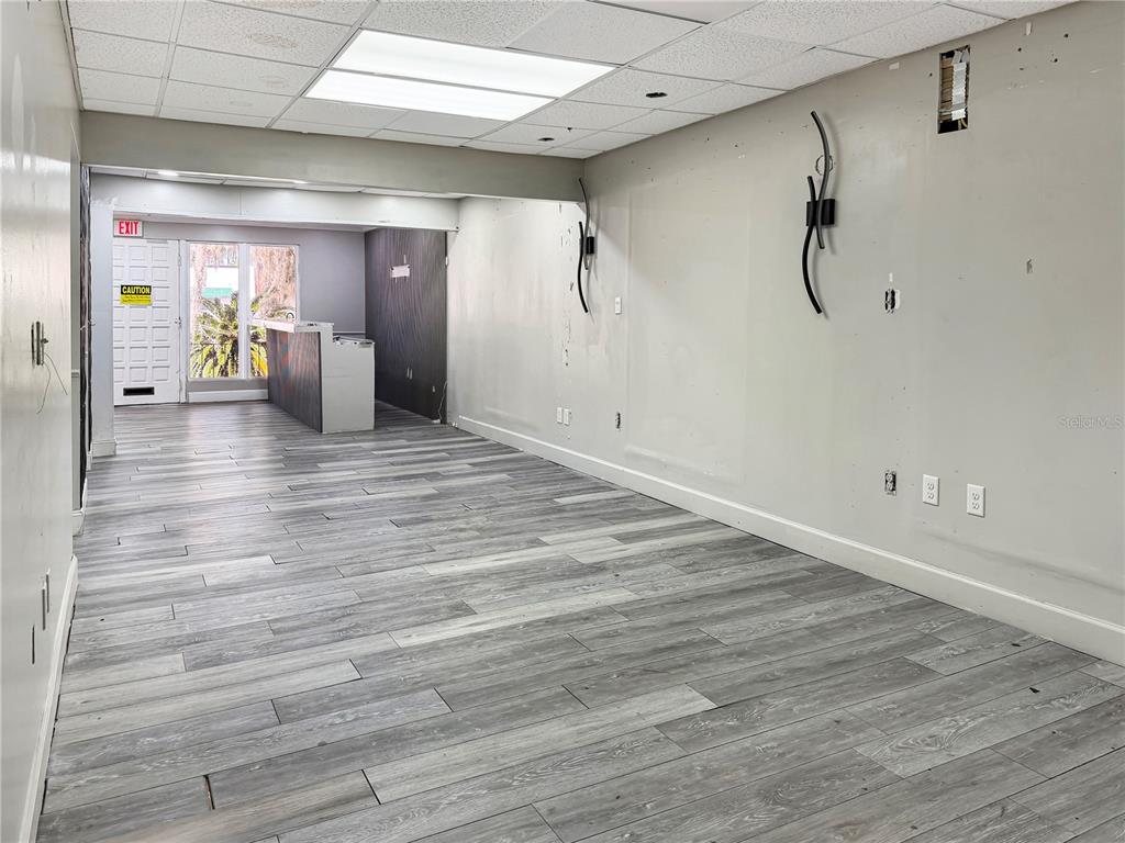 An empty commercial space features gray wood-look flooring, white walls, and a drop ceiling — 4131 UNIVERSITY BOULEVARD S UNIT 5, JACKSONVILLE, FL
