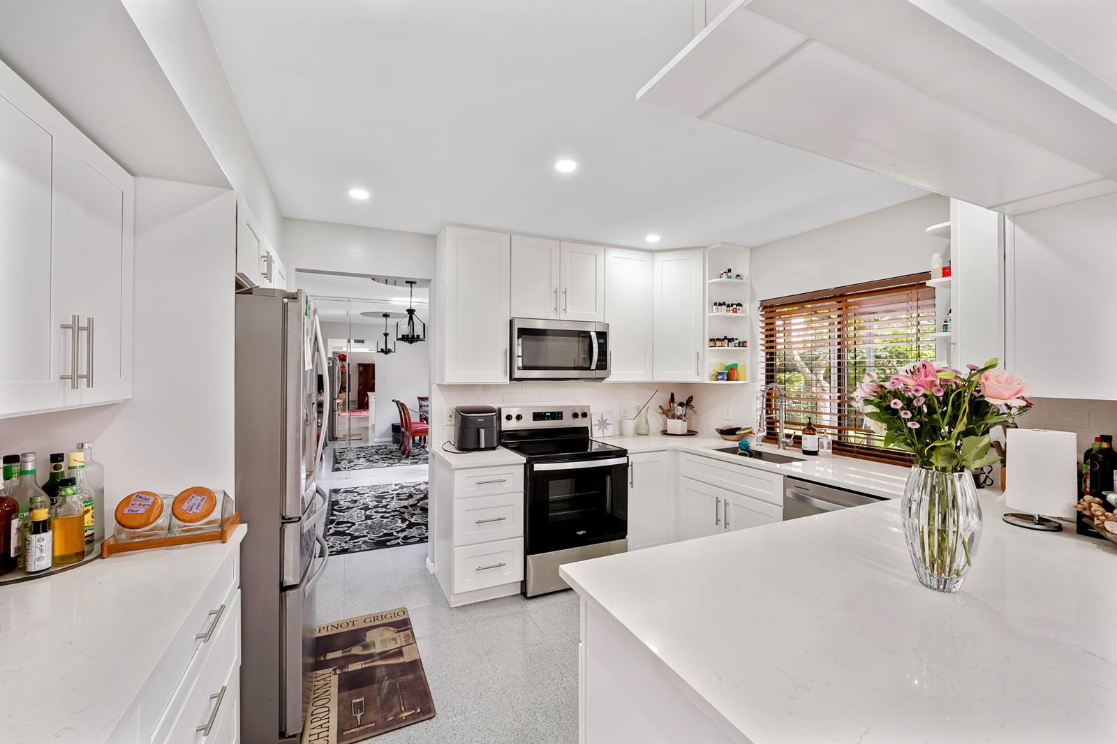 A bright kitchen features white cabinets, stainless steel appliances, and a quartz-topped peninsula — 6840 W Wedgewood Avenue, Davie FL 33331, DAVIE, FL