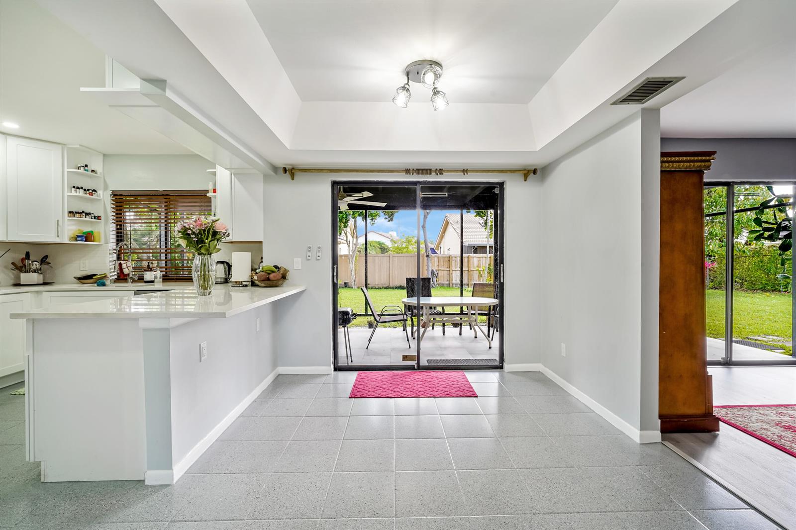 A kitchen and dining area with gray tile floors, white cabinets, and sliding glass doors — 6840 W Wedgewood Avenue, Davie FL 33331, DAVIE, FL