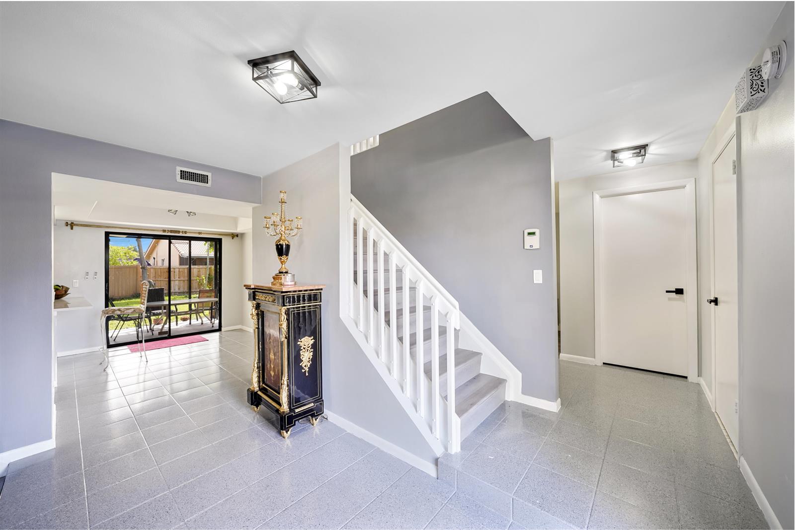 An entryway features gray tile flooring, a staircase with white railings, and a decorative cabinet — 6840 W Wedgewood Avenue, Davie FL 33331, DAVIE, FL