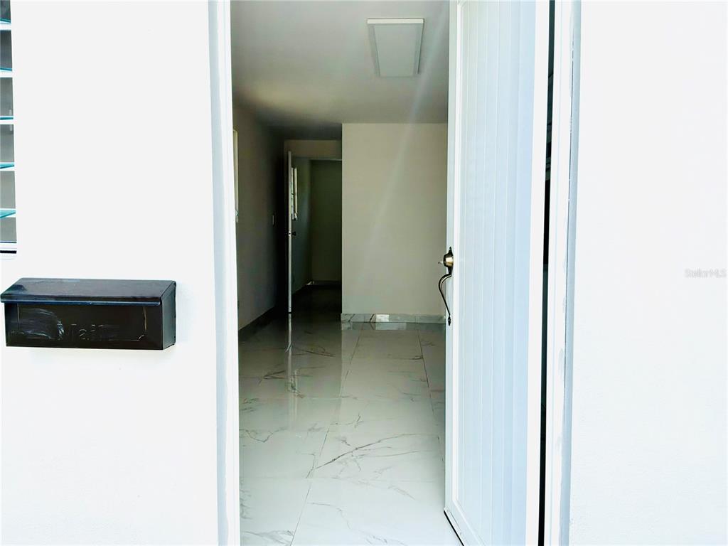 A view through an open white door into a room with white marble-patterned tile flooring — 312 Loiza LAS CUMBRES #II, SAN JUAN, PR