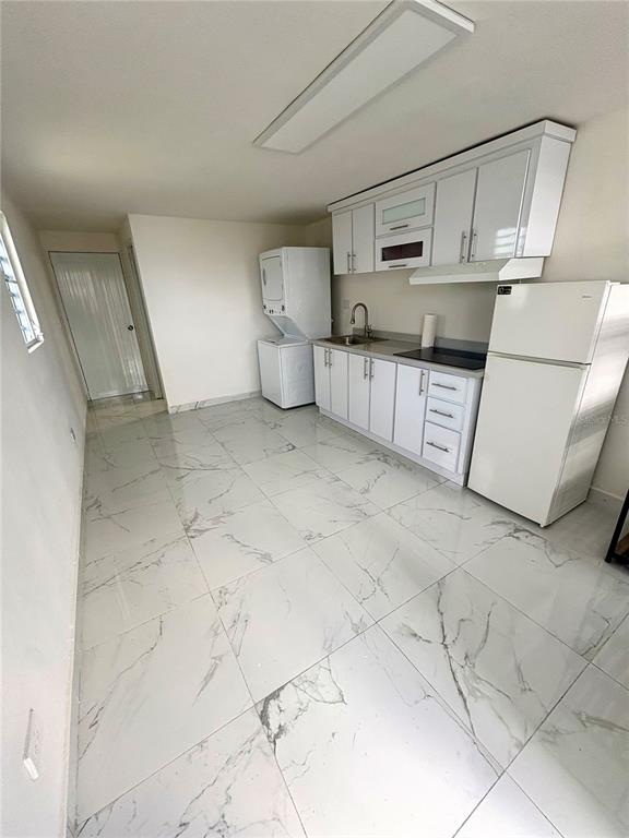 A kitchen with white cabinets, a refrigerator, a stacked washer-dryer, and white marble-patterned tile floors — 312 Loiza LAS CUMBRES #II, SAN JUAN, PR