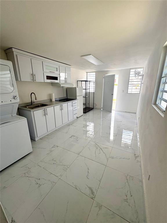 A kitchen with white cabinets, marble-look tile flooring, and a stacked washer-dryer unit — 312 Loiza LAS CUMBRES #II, SAN JUAN, PR
