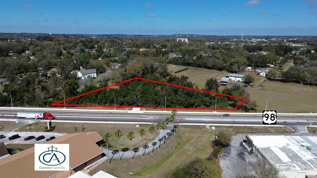 An aerial view shows a wooded, triangular plot of land adjacent to a highway — US HWY 98 BYPASS, DADE CITY, FL