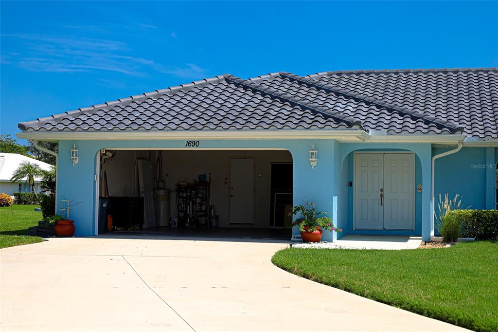 A light blue house exterior features a two-car garage and a double-door front entrance — 1690 WAXWING COURT, VENICE, FL