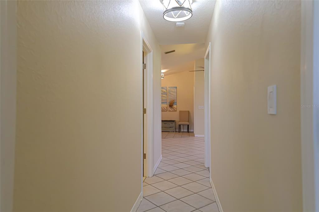 A hallway with light-colored walls and diagonal floor tiles leads to an open living area — 1690 WAXWING COURT, VENICE, FL