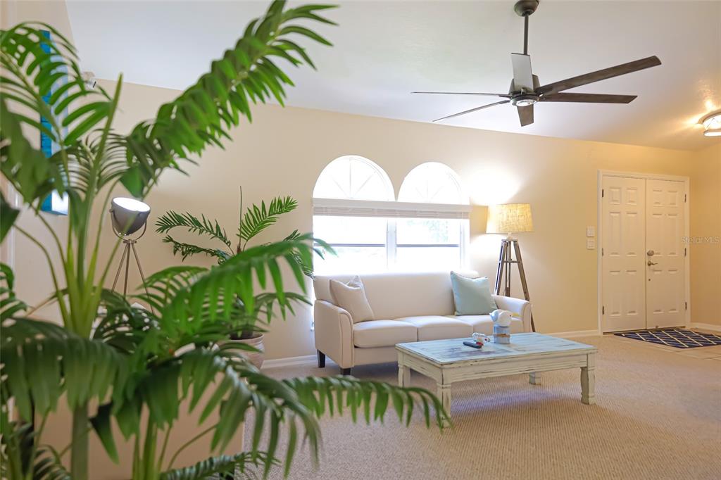 A living room features a white sofa, a distressed coffee table, and a ceiling fan — 1690 WAXWING COURT, VENICE, FL
