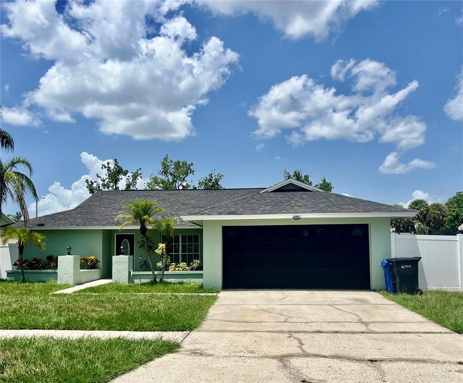 A single-story house with light green siding, a dark garage door, and a shingled roof — 10902 WINGATE DRIVE, TAMPA, FL