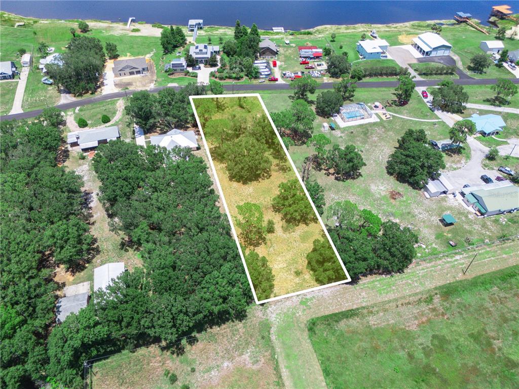 An aerial view shows a rectangular, tree-dotted vacant lot outlined in white near a lake — 735 KEEN ROAD, FROSTPROOF, FL