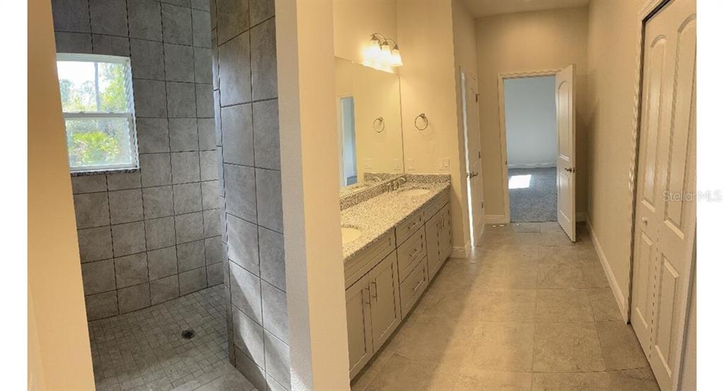 A bathroom features a tiled walk-in shower, a double-sink vanity, and light-colored tile flooring — 1189 DELMONTE STREET, NORTH PORT, FL