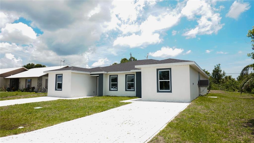 A single-story house with white stucco walls, dark window frames, and a paved driveway — 12 TROUT WAY UNIT A, KISSIMMEE, FL