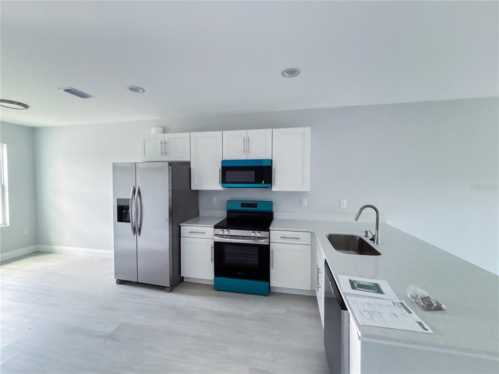 A kitchen features white cabinets, stainless steel appliances, and a light-colored countertop — 12 TROUT WAY UNIT A, KISSIMMEE, FL