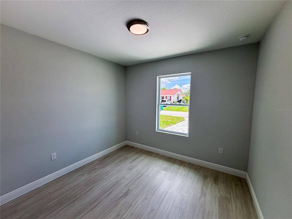 An empty bedroom features light gray walls, wood-look flooring, and a single window — 12 TROUT WAY UNIT A, KISSIMMEE, FL