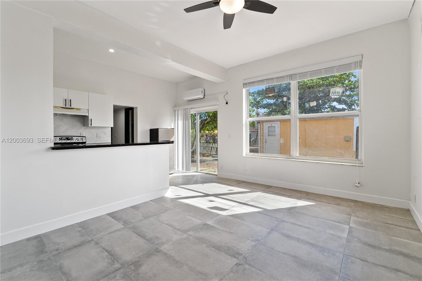 A bright living area features gray tile floors, a kitchen pass-through, and a ceiling fan — 2204 Mckinley St, Hollywood FL 33020, HOLLYWOOD, FL