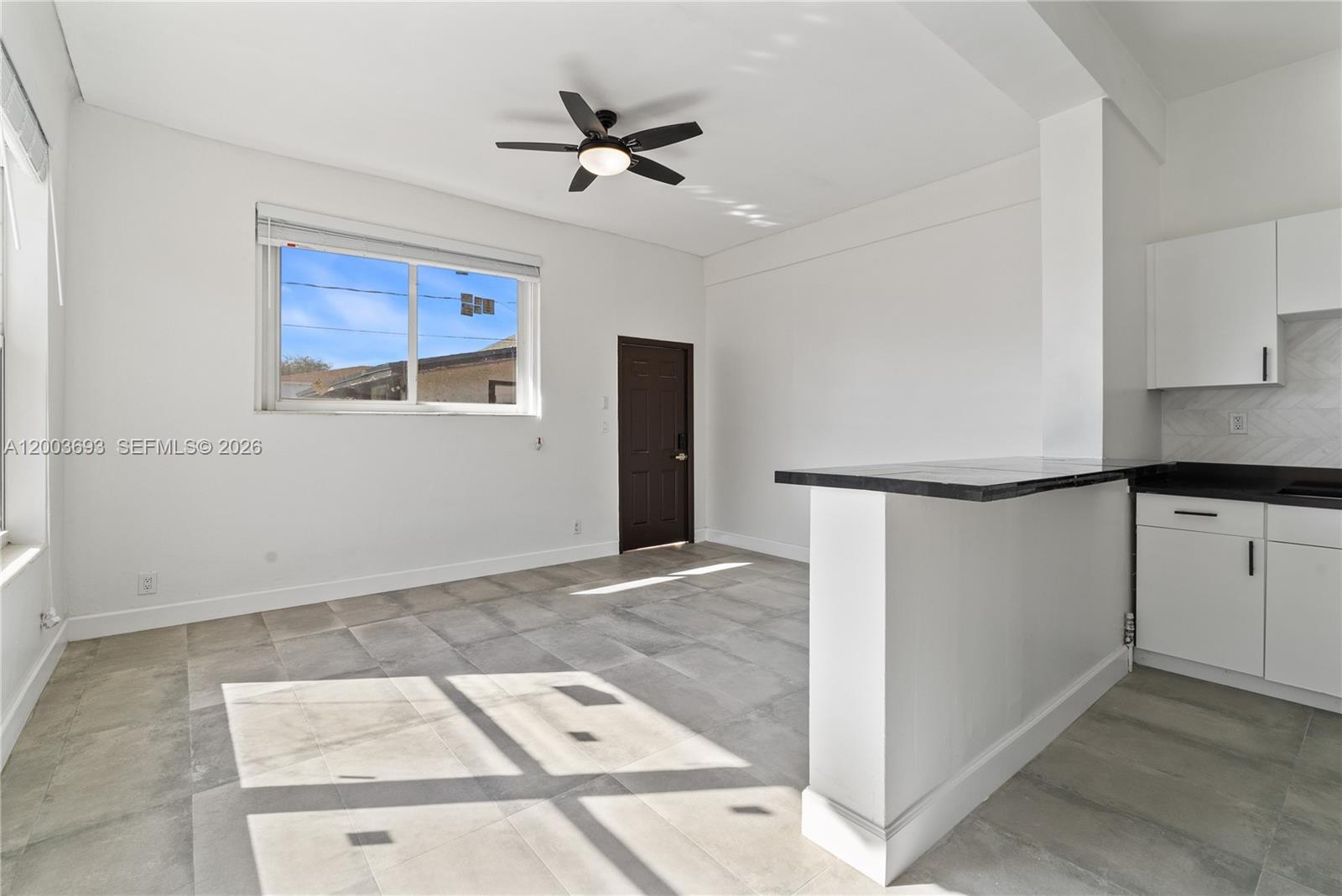 A room with gray tile floors, a ceiling fan, a window, and a kitchen counter — 2204 Mckinley St, Hollywood FL 33020, HOLLYWOOD, FL