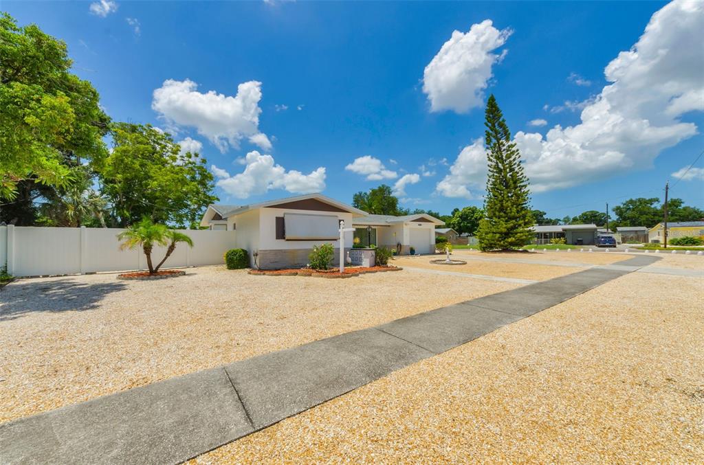 A single-story house with a gravel front yard and a concrete walkway under a blue sky — 5992 32ND AVENUE N, ST PETERSBURG, FL