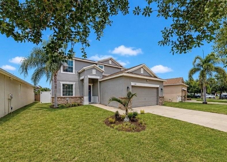 A two-story suburban house with a gray exterior, stone accents, and a two-car garage — 509 POWDER VIEW DRIVE, RUSKIN, FL