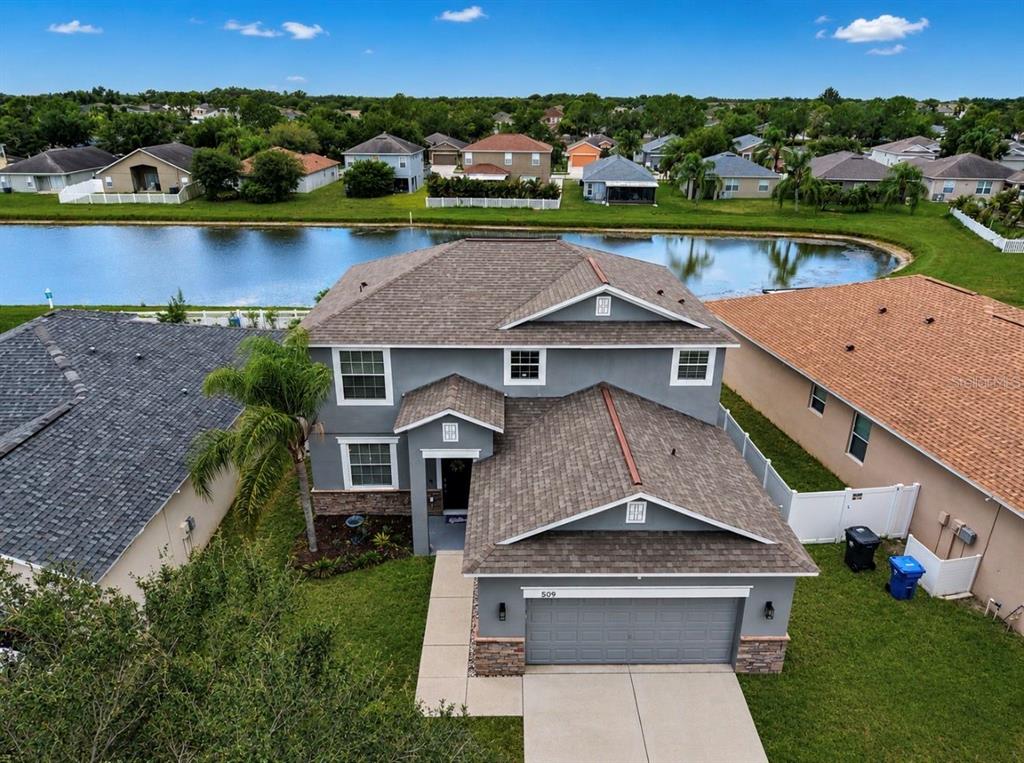 An aerial view of a two-story gray house with a garage and a backyard pond — 509 POWDER VIEW DRIVE, RUSKIN, FL