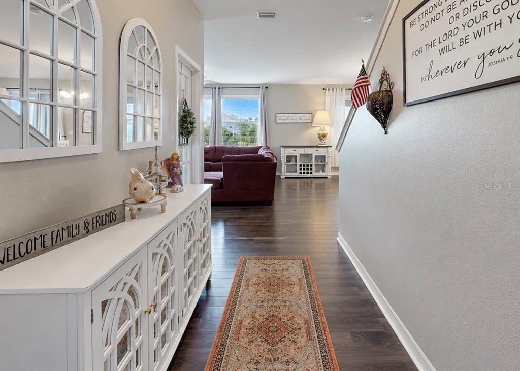 A hallway with a white console table leads to a living room with dark flooring — 509 POWDER VIEW DRIVE, RUSKIN, FL