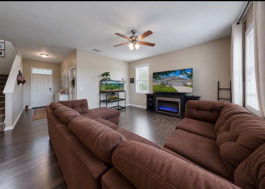 A living room features a large brown sectional sofa, a fireplace console, and dark flooring — 509 POWDER VIEW DRIVE, RUSKIN, FL