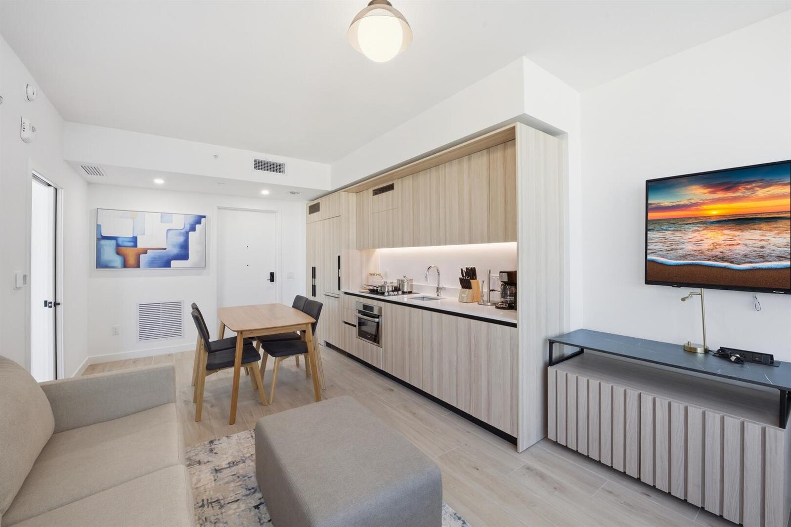 A modern studio apartment features a kitchenette with light wood cabinets and a dining area — 225 N Miami Avenue # 2002, Miami FL 33128, MIAMI, FL
