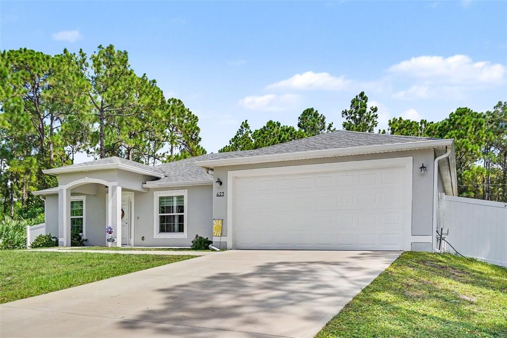 A single-story house with a white garage, gray exterior, and a concrete driveway — 427 SE FLAGLER RD, PALM BAY, FL