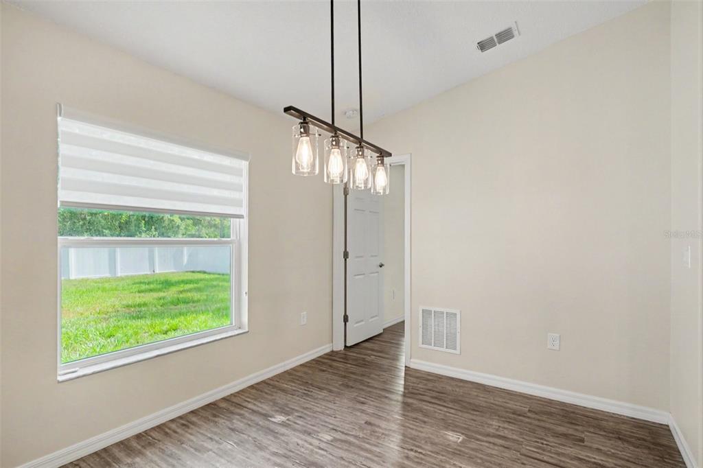 A dining area with wood-look flooring, a modern pendant light, and a window overlooking a yard — 427 SE FLAGLER RD, PALM BAY, FL
