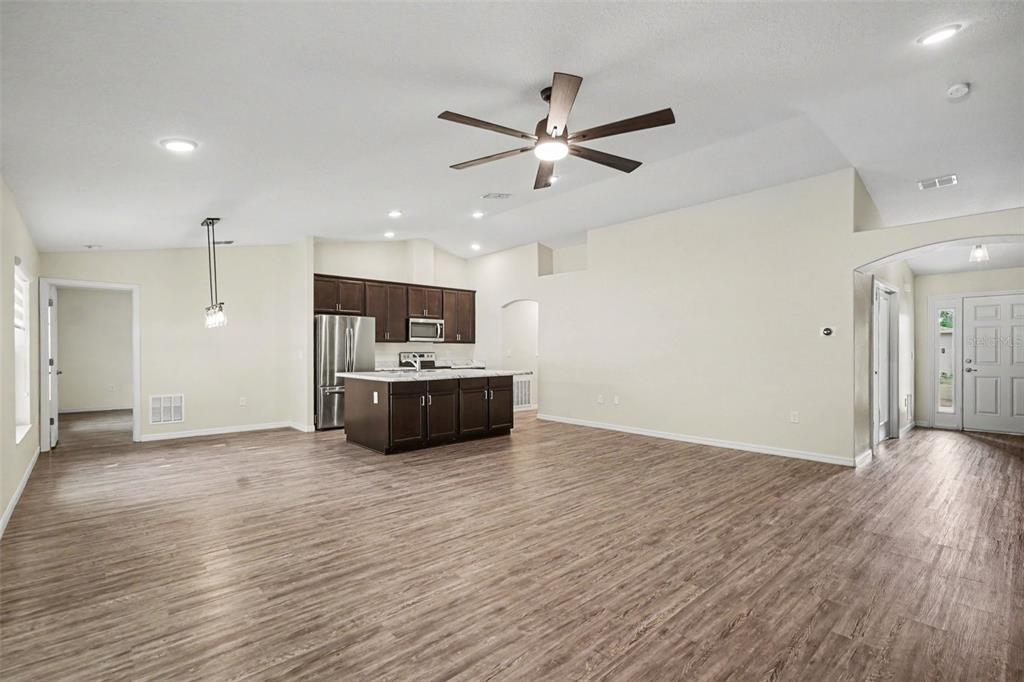 An open-concept living area features wood-look flooring, a kitchen island, and dark wood cabinetry — 427 SE FLAGLER RD, PALM BAY, FL