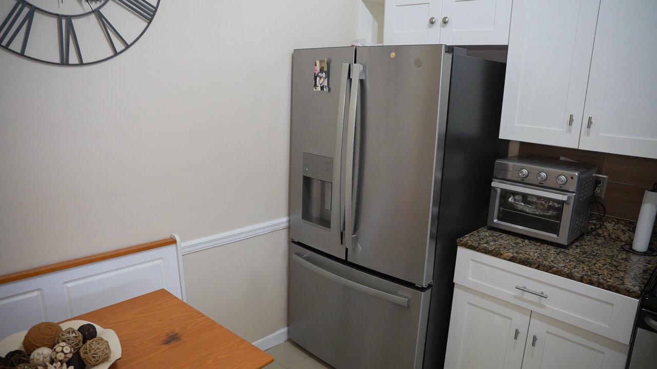 A stainless steel refrigerator sits next to white cabinets and a countertop toaster oven — 201 Maplewood Drive # 201, FL 33415, FL