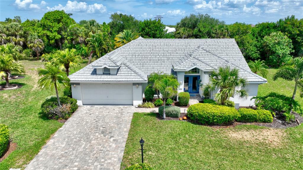 An aerial view of a single-story house with a gray tile roof and paver driveway — 24050 REDFISH COVE DRIVE, PUNTA GORDA, FL