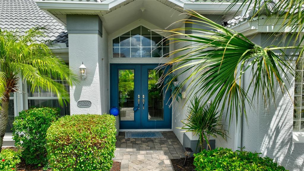 The exterior of a home features a blue double front door and a paved entryway — 24050 REDFISH COVE DRIVE, PUNTA GORDA, FL