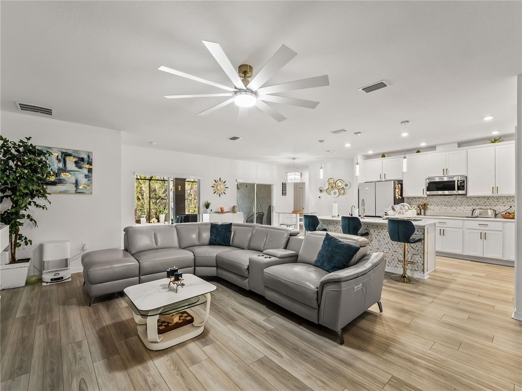 A modern open-concept living room and kitchen featuring a grey sectional sofa and white cabinetry — 1367 MILIKEN TERRACE, PORT CHARLOTTE, FL