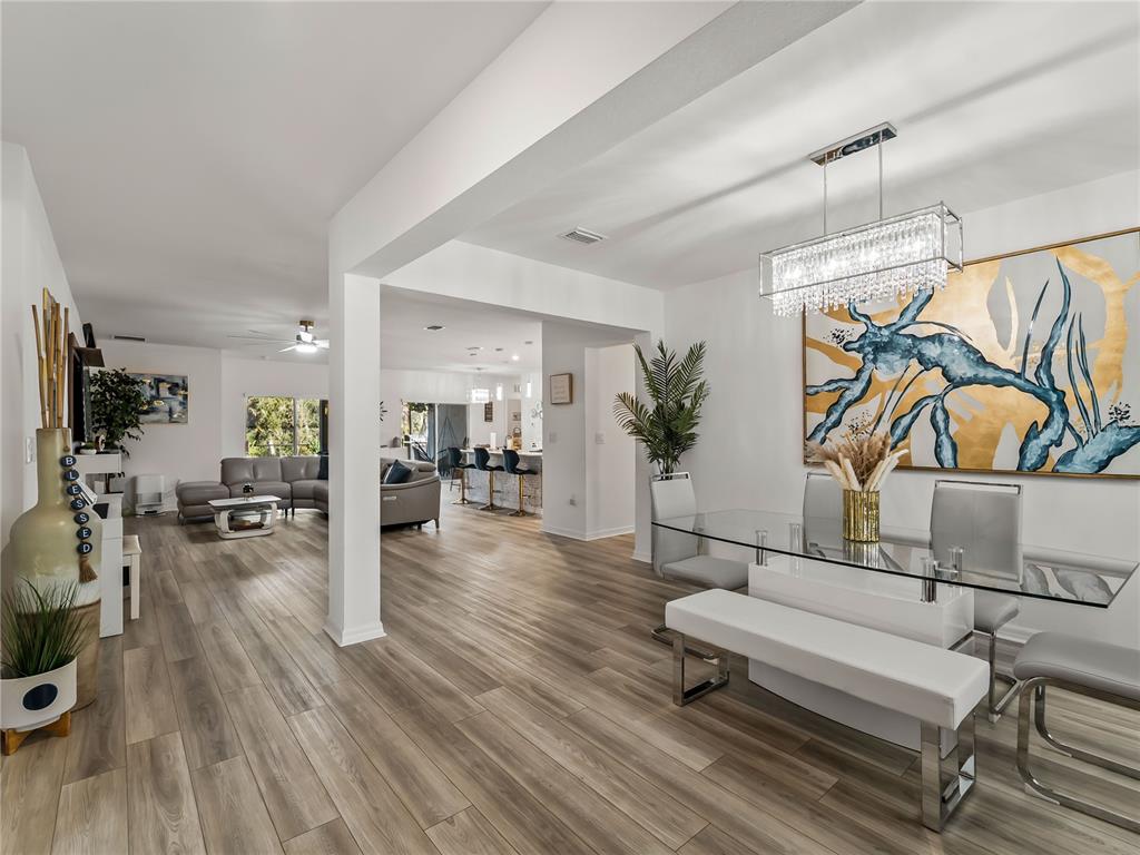 An open-concept dining area and living room feature light wood-look flooring and modern decor — 1367 MILIKEN TERRACE, PORT CHARLOTTE, FL