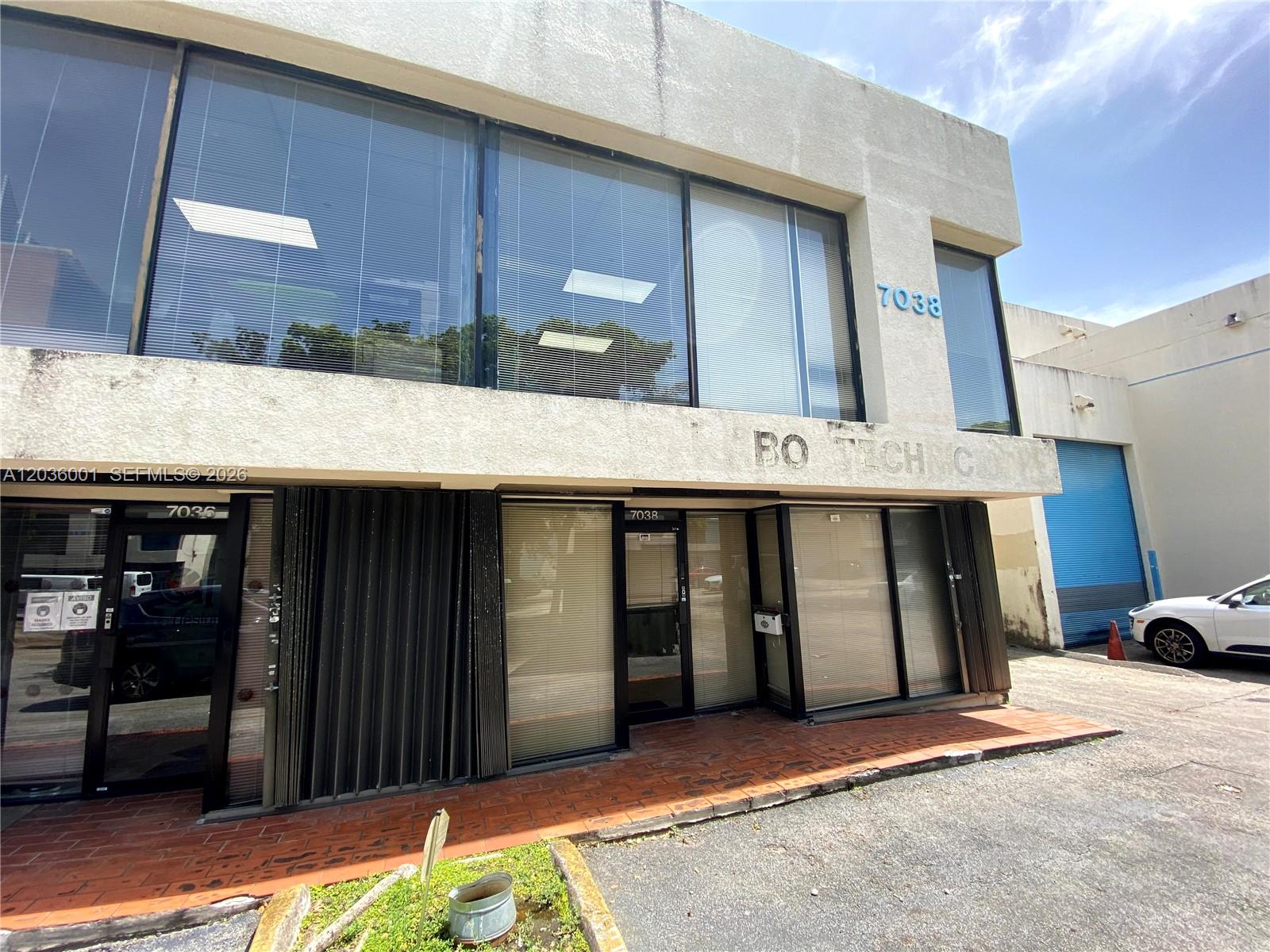 The exterior of a two-story commercial building features large windows, glass doors, and brick flooring — 7038 NW 50th St # 2, Miami FL 33166, MIAMI, FL