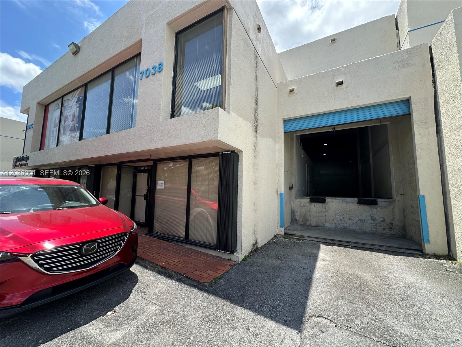 A two-story commercial building features a red car parked in front of a loading dock — 7038 NW 50th St # 2, Miami FL 33166, MIAMI, FL