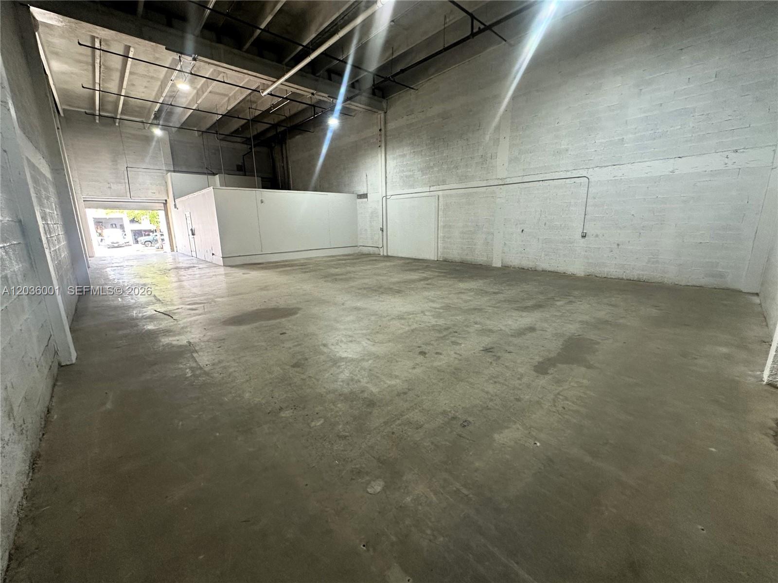 An empty industrial warehouse space features concrete floors, white block walls, and exposed ceiling rafters — 7038 NW 50th St # 2, Miami FL 33166, MIAMI, FL