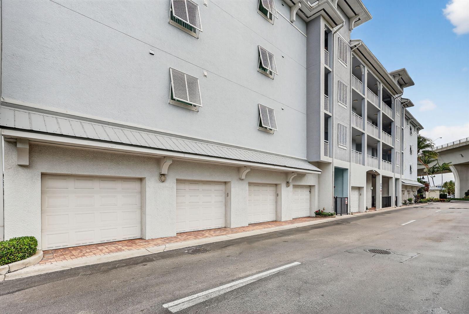 The exterior of a multi-story building features several garage doors and shuttered windows — 675 NW Flagler Avenue Unit 202, Stuart FL 34994, STUART, FL