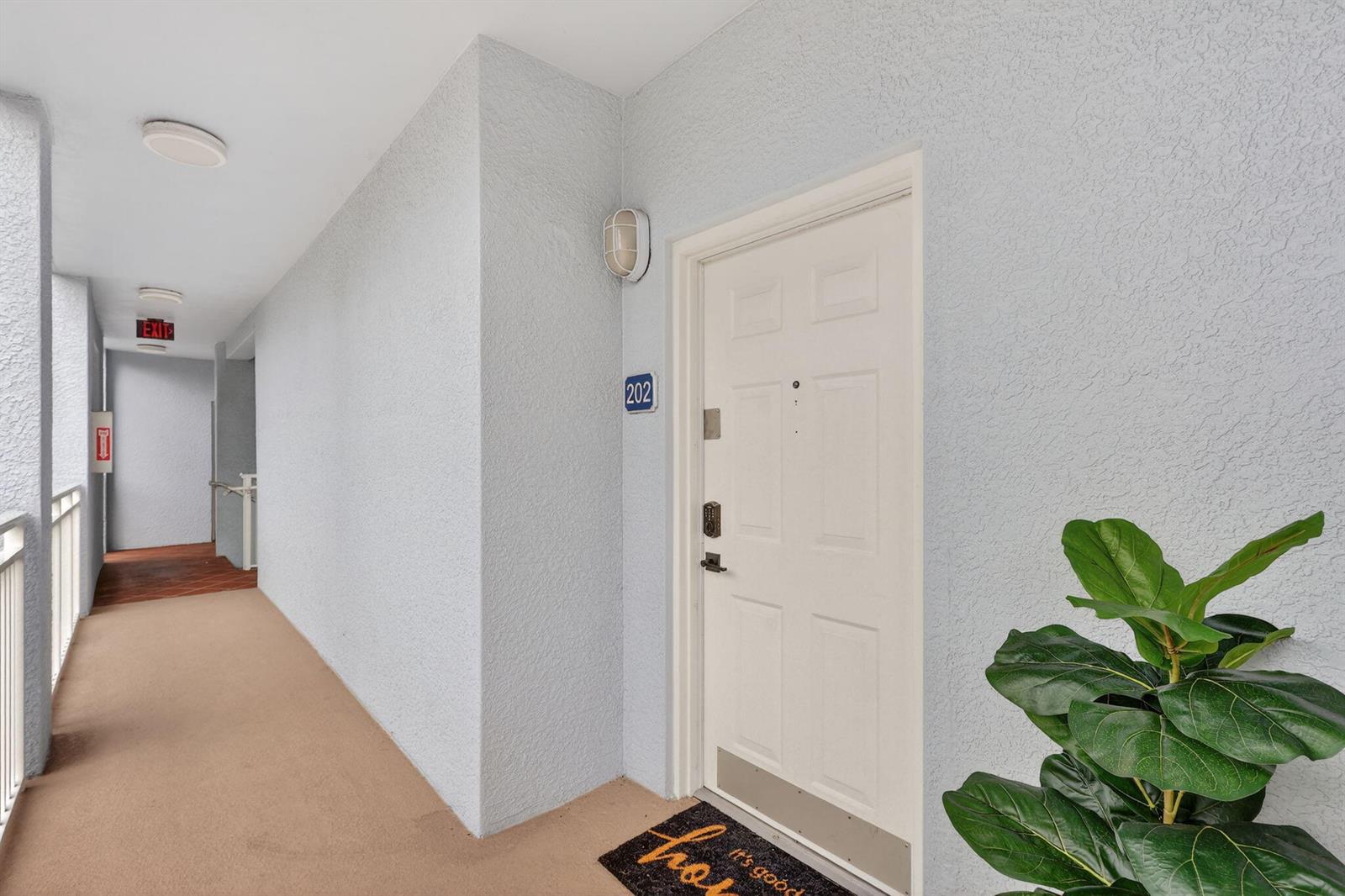 An exterior hallway shows the entrance to apartment 202 with a potted plant nearby — 675 NW Flagler Avenue Unit 202, Stuart FL 34994, STUART, FL