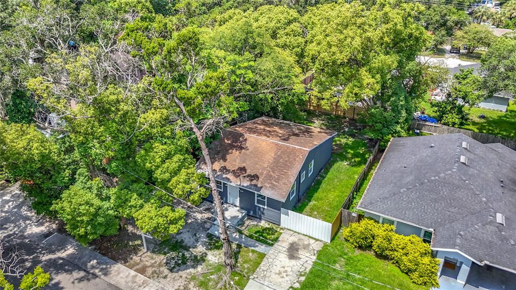 An aerial view shows a small gray house with a brown roof surrounded by trees — 8010 N 13TH STREET, TAMPA, FL