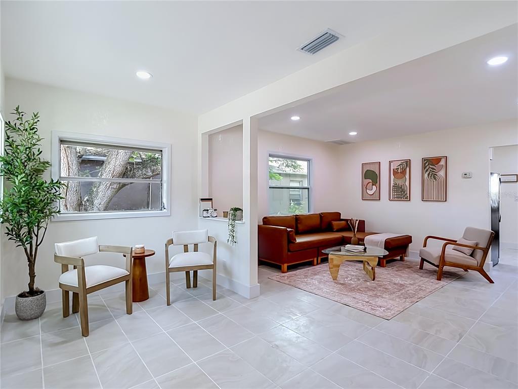 A bright living area features light tile floors, a leather sectional, and two white chairs — 8010 N 13TH STREET, TAMPA, FL