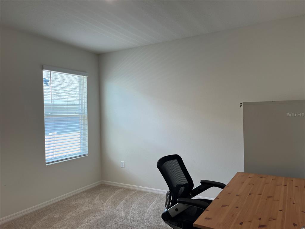 A home office features a wooden desk, an ergonomic chair, carpeted flooring, and a window — 3031 STATEN DRIVE, DELTONA, FL