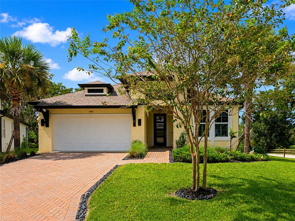 A single-story house with a yellow exterior, a paved driveway, and a palm tree at sunset — 14941 BARROWS BLUFF TERRACE, BRADENTON, FL