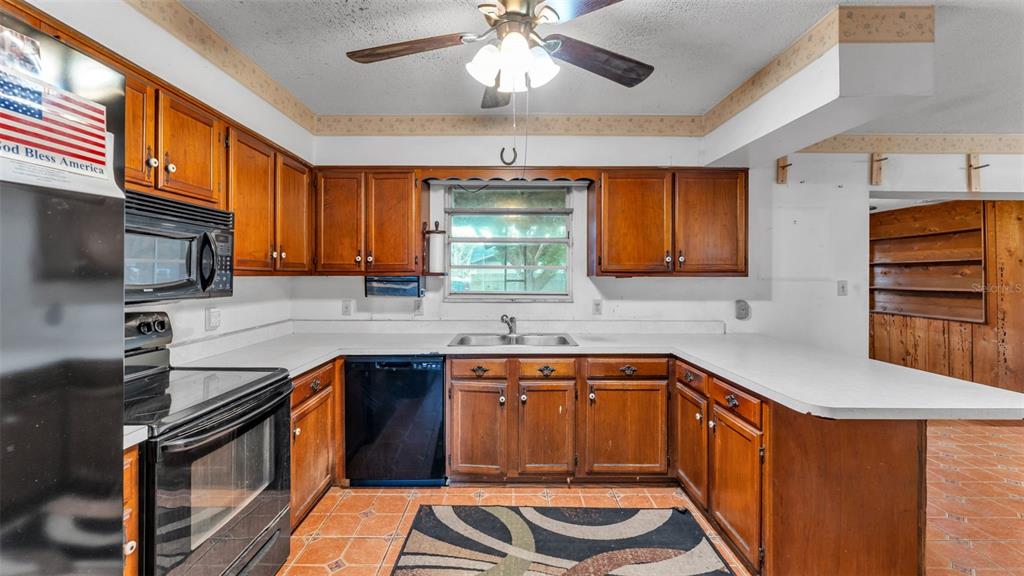 A kitchen features wood cabinets, white countertops, a black dishwasher, and a ceiling fan — 4104 E COUNTY ROAD 540A, LAKELAND, FL