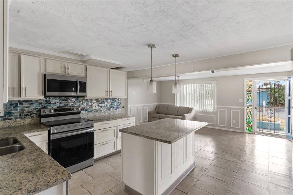 A kitchen with granite countertops, white cabinetry, a center island, and a tiled floor — 2344 TAHITIAN DRIVE, HOLIDAY, FL