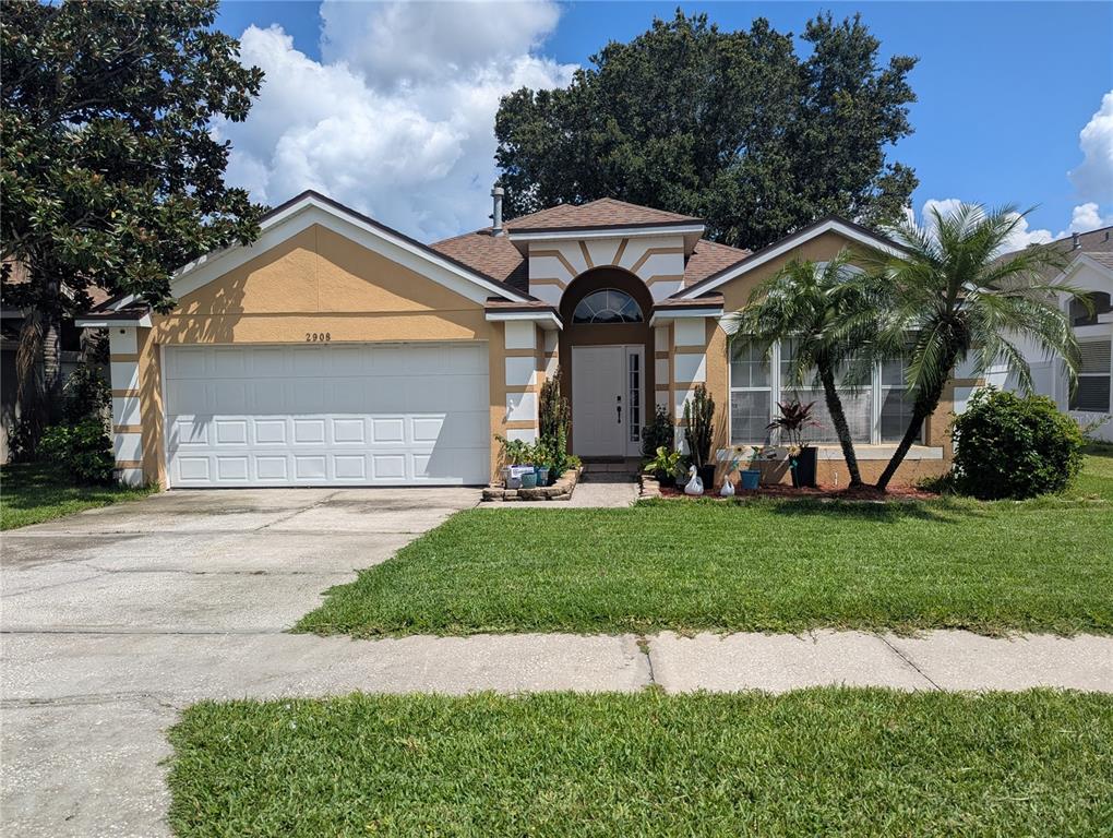A single-story house with a tan stucco exterior, white trim, a two-car garage, and palm trees — 2908 EGRETS LANDING, LAKE MARY, FL