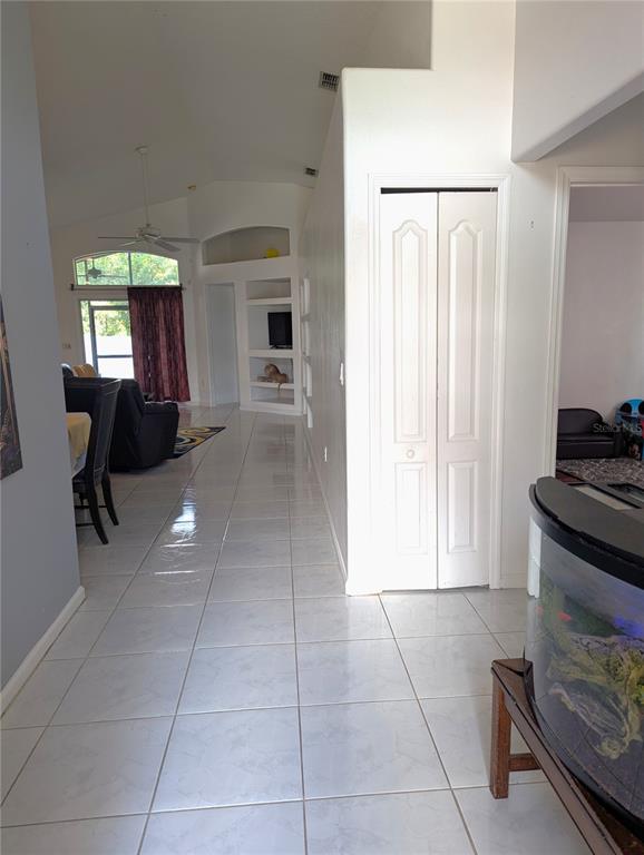 A tiled hallway leads past a white closet and built-in shelving toward a living area — 2908 EGRETS LANDING, LAKE MARY, FL