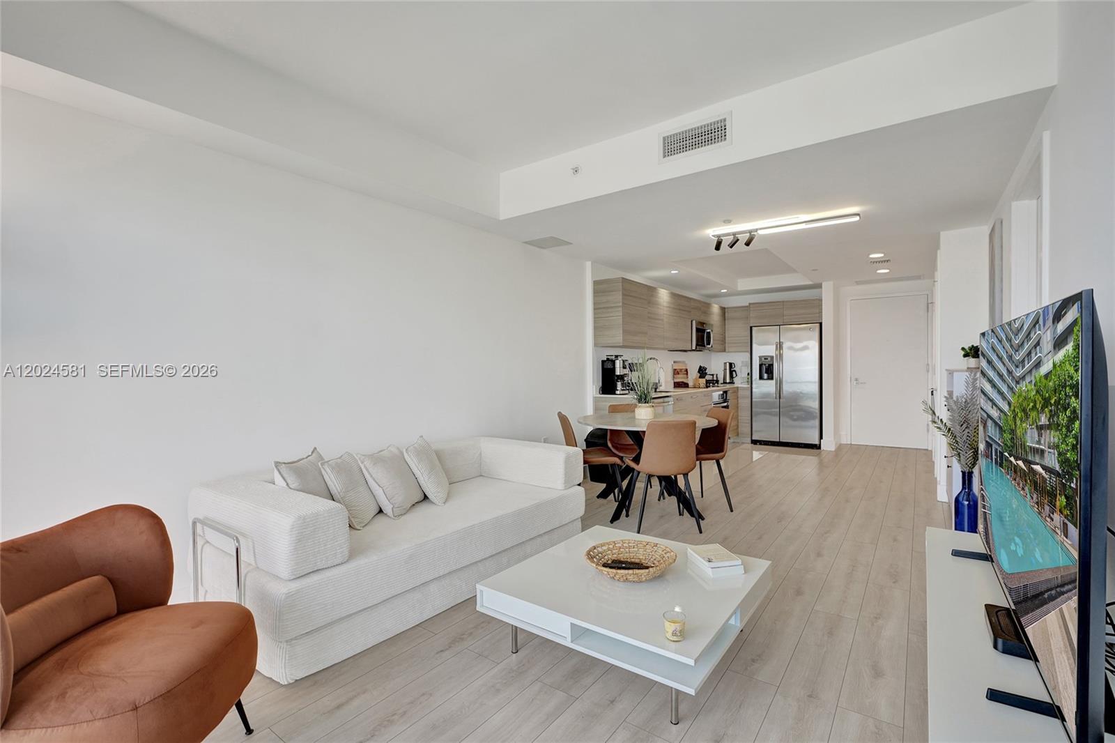 This open-concept living and dining area features light wood flooring and a modern kitchen — 121 NE 34th St # 2310, Miami FL 33137, MIAMI, FL