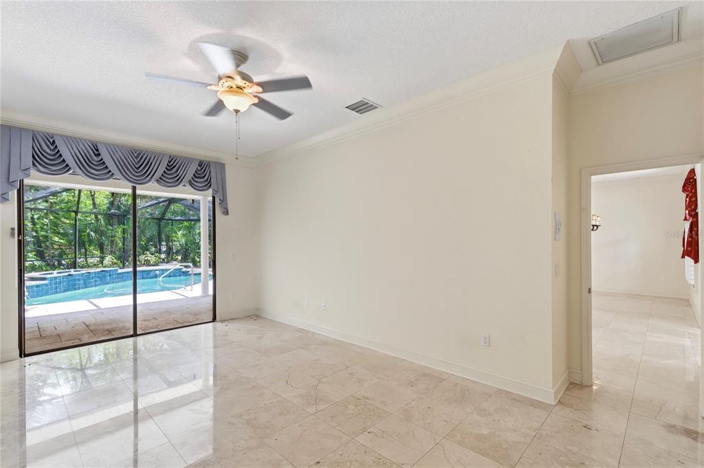 A bright room with tile floors, a ceiling fan, and sliding doors opening to a pool — 50 KELLEYS TRAIL, OLDSMAR, FL