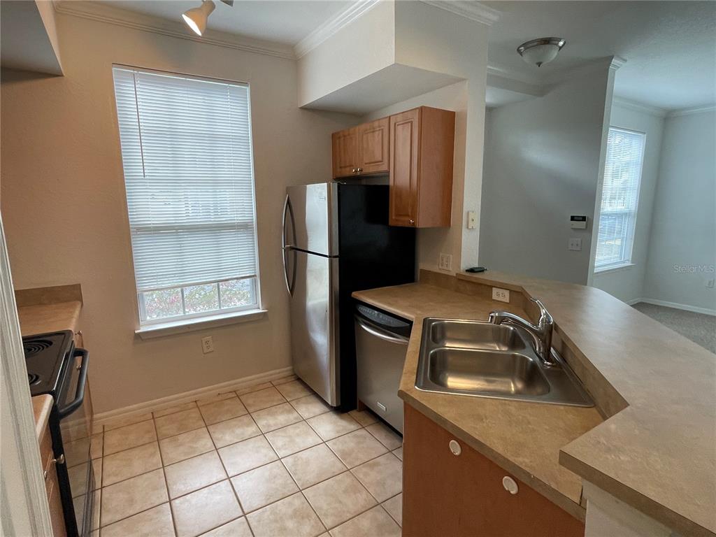 A kitchen features tile flooring, stainless steel appliances, wood cabinets, and a laminate countertop — 5500 ROSEHILL ROAD UNIT 103, SARASOTA, FL