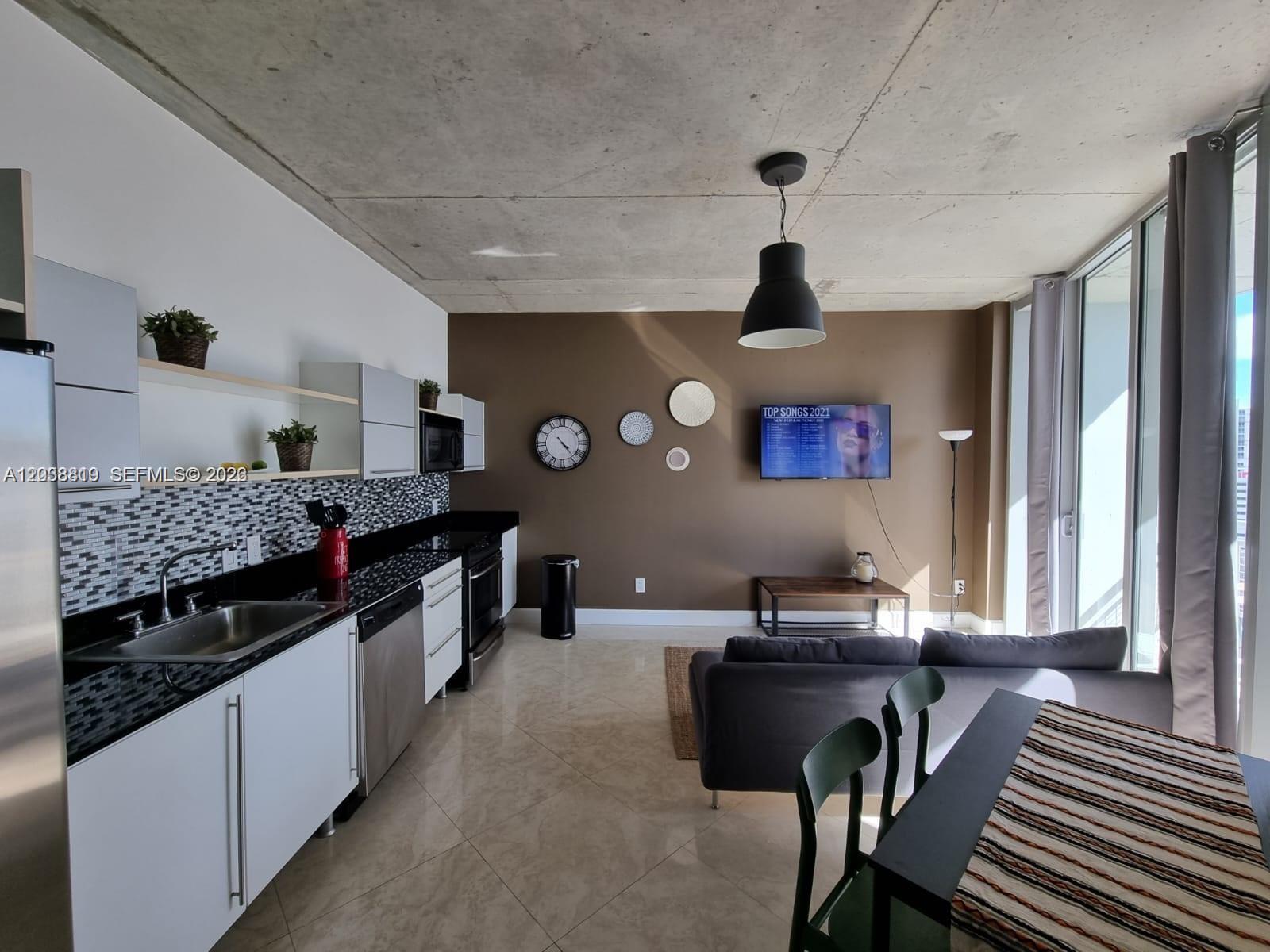 A modern open-concept kitchen and living area features concrete ceilings, tile floors, and brown walls — 690 SW 1st Ct # 1827, Miami FL 33130, MIAMI, FL